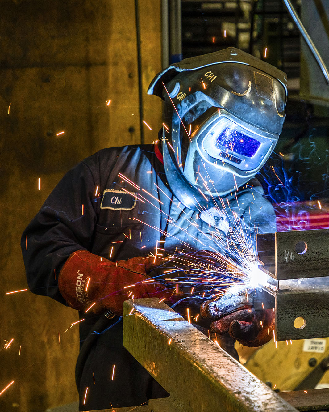 A person working in a factory with a welding machine.