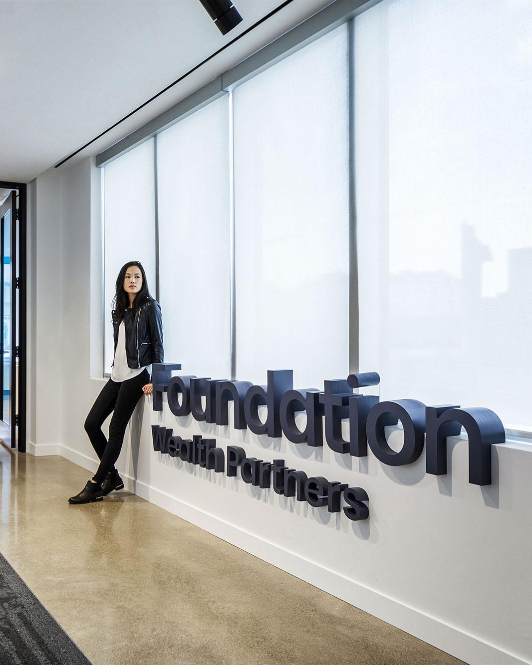 Image of a woman posing by a company name wall sign.